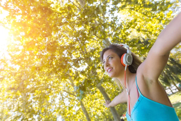 Mooie jonge vrouw luisteren muziek in het Park — Stockfoto