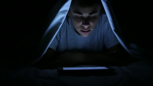 Frau schaut Horrorfilm auf digitalem Tablet unter Bettlaken — Stockvideo
