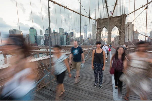 Jonge vrouw op Brooklyn Bridge met wazig mensen passeren Aroun — Stockfoto