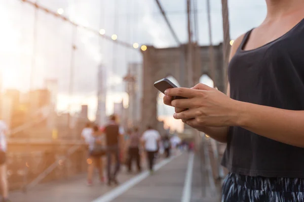 Mujer joven usando teléfono inteligente en el puente de Brooklyn —  Fotos de Stock