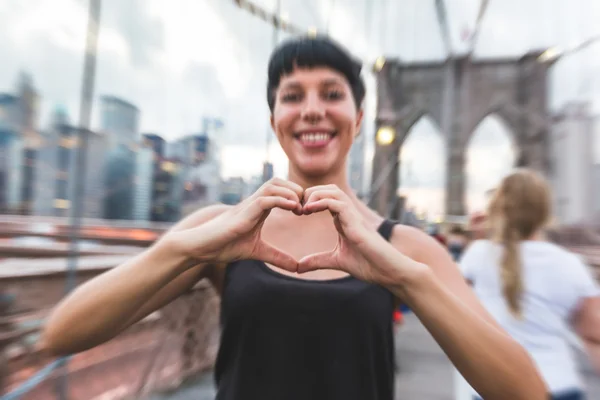 Ung kvinna med hjärtat formade händerna på Brooklyn Bridge — Stockfoto