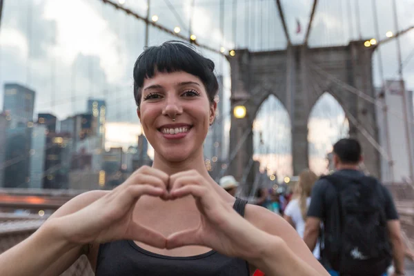 Młoda kobieta z sercem w kształcie ręce na Brooklyn Bridge — Zdjęcie stockowe