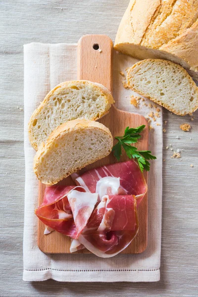 Tranches de pain et jambon sur une planche à découper — Photo