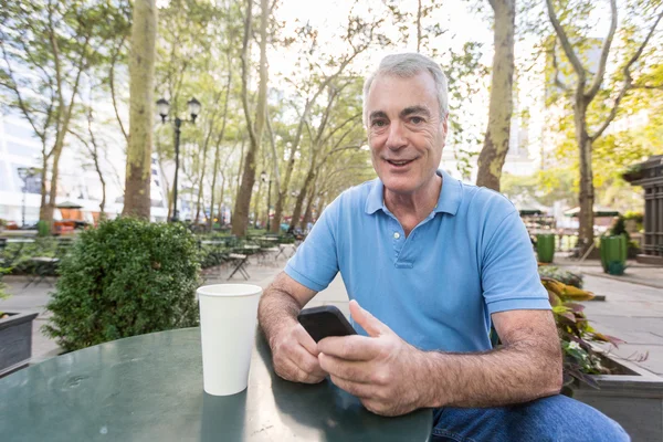 Amerikanischer Senior mit Handy im Park — Stockfoto