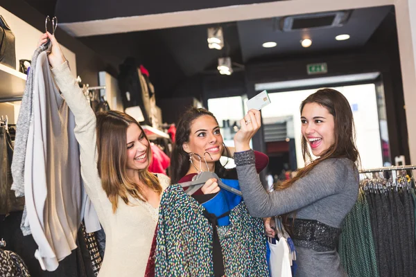 Mulheres felizes com cartão de crédito em uma loja de roupas — Fotografia de Stock