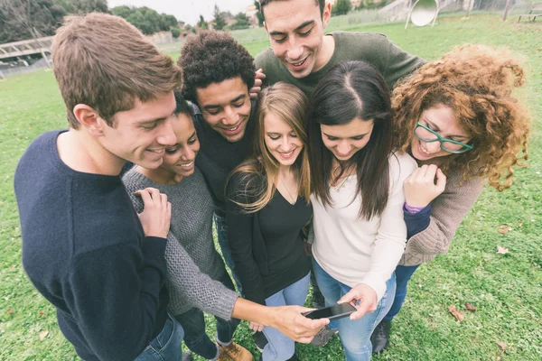 Grupo multiétnico de amigos mirando el teléfono móvil — Foto de Stock