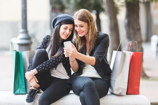 Mujeres con teléfono inteligente y bolsas de compras — Foto de Stock