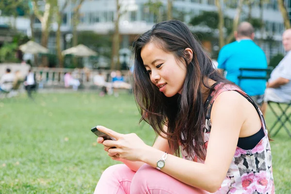 Menina digitando no telefone no parque — Fotografia de Stock