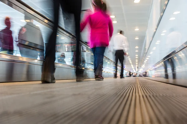 Suddiga människor gå på flygplatsen gångväg — Stockfoto