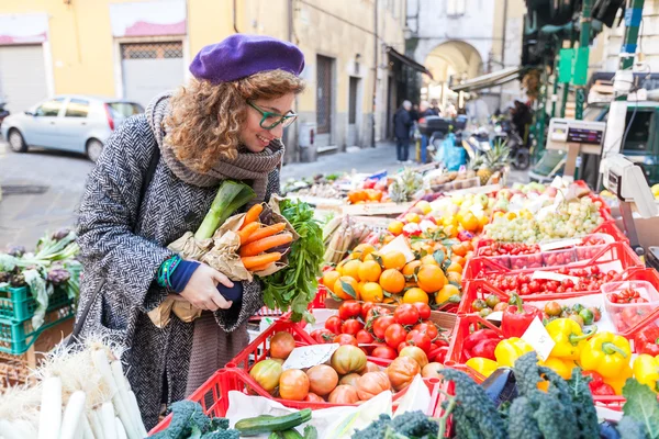 Junge Frau kauft Gemüse auf lokalem Markt — Stockfoto