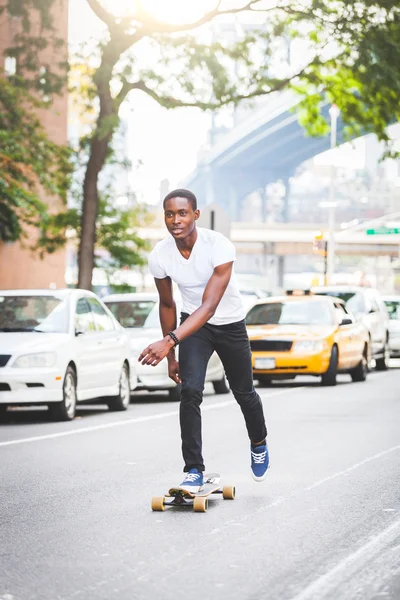 Zwarte jongen op de weg met Longboard skaten — Stockfoto