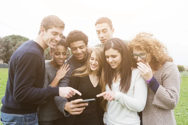 Multi-etnische groep van vrienden kijken naar mobiele telefoon — Stockfoto