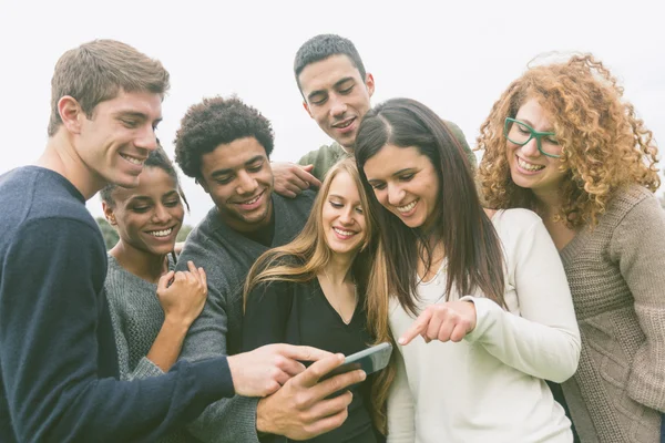 Multiethnische Freundesgruppe schaut auf Mobiltelefon Stockbild