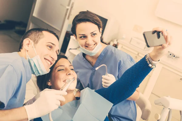 Feliz paciente, dentista y asistente tomando selfie todos juntos . — Foto de Stock