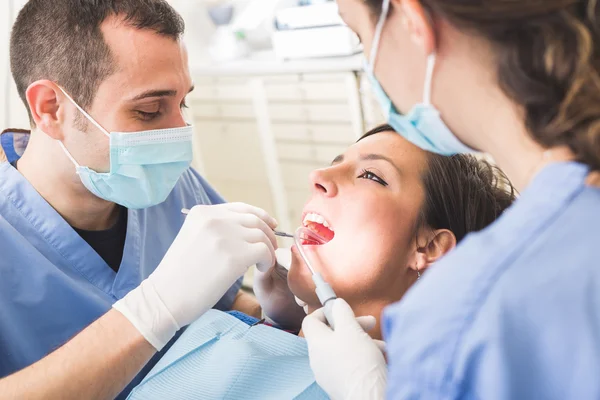 Dentista y asistente dental examinando los dientes del paciente . — Foto de Stock