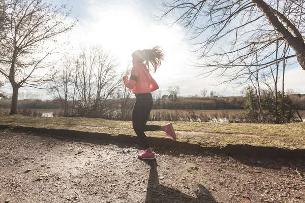 Joven mujer corriendo en el camino fuera de la carretera por la mañana . —  Fotos de Stock