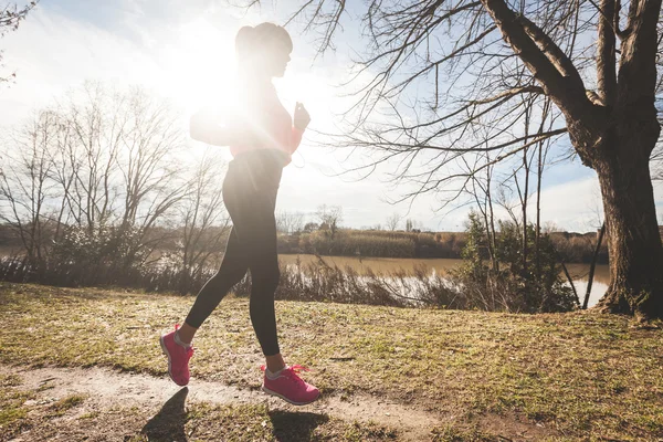 Joven mujer corriendo en el camino fuera de la carretera por la mañana . — Foto de Stock