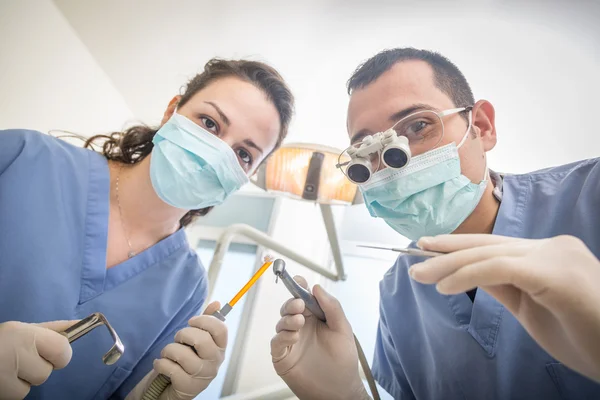 Dentistas alegres segurando ferramentas dentárias olhando para a câmera . — Fotografia de Stock