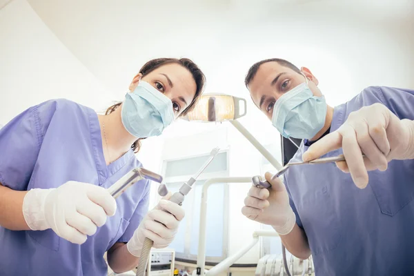 Dentistes joyeux tenant des outils dentaires regardant la caméra . — Photo