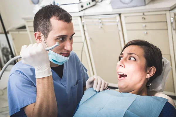 Dentista asustando a paciente con el taladro . — Foto de Stock