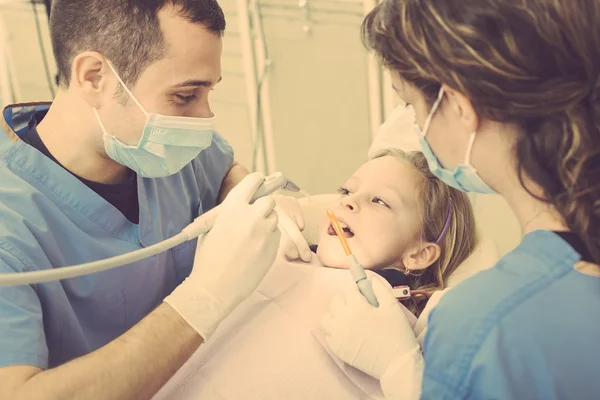 歯科医と歯科助手の若い少女の歯を調べること. — ストック写真