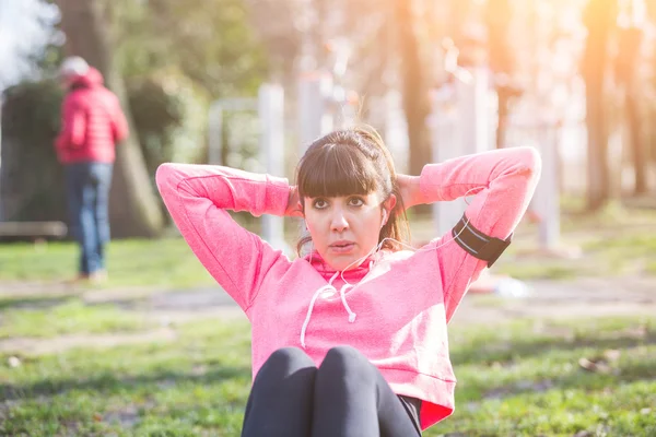 Mujer joven haciendo ejercicios abdominales en el parque . —  Fotos de Stock