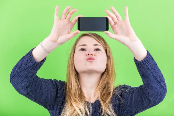 Mujer joven tomando una selfie sobre fondo verde . — Foto de Stock