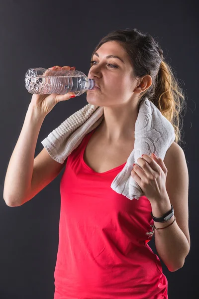 Deportiva mujer joven bebiendo agua sobre fondo negro . —  Fotos de Stock