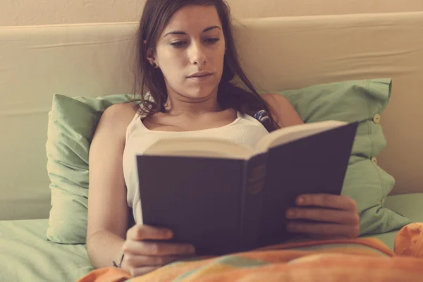 Mujer joven leyendo un libro en la cama —  Fotos de Stock