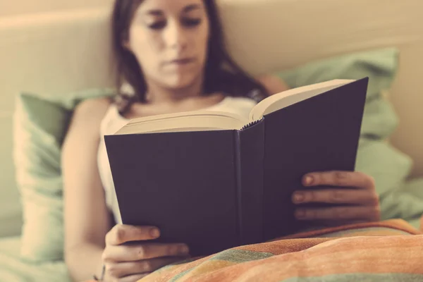 Junge Frau liest ein Buch auf dem Bett — Stockfoto