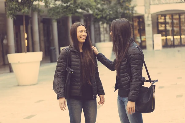 Женщины-близнецы разговаривают друг с другом на городской площади . — стоковое фото