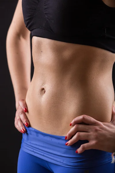 Deportiva mujer sudoroso abdomen sobre fondo negro — Foto de Stock