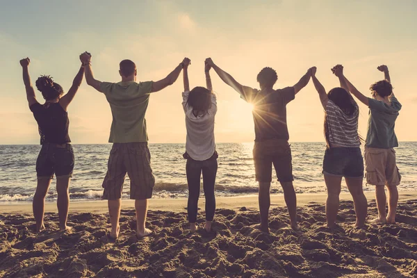 Multirassische Gruppe von Menschen mit erhobenen Armen beim Blick auf den Sonnenuntergang — Stockfoto