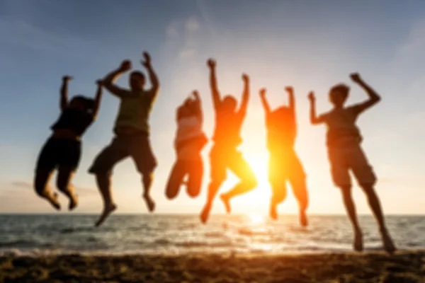 Group of people jumping at beach, blurred background. — Stock Photo, Image