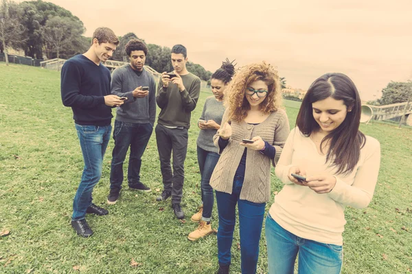 Sekelompok teman multietnis melihat ponsel pintar mereka sendiri — Stok Foto