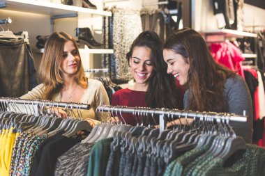 Üç kadın bir elbise seçimi bir giyim mağazası