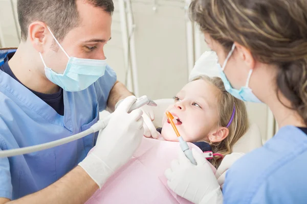 Dentista e dentista assistente esaminando giovani ragazza denti — Foto Stock