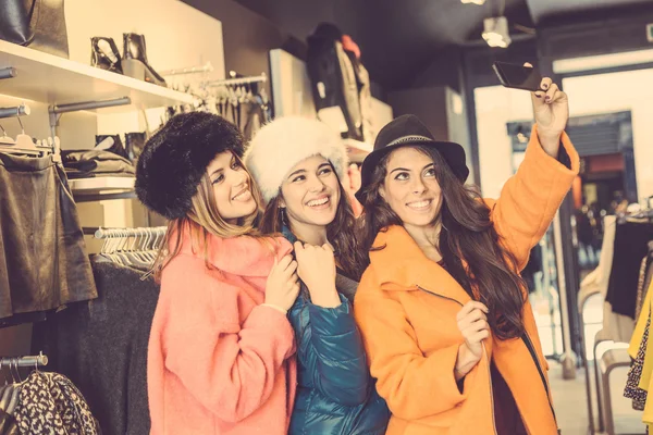 Três mulheres tomando uma selfie vestindo casacos coloridos — Fotografia de Stock