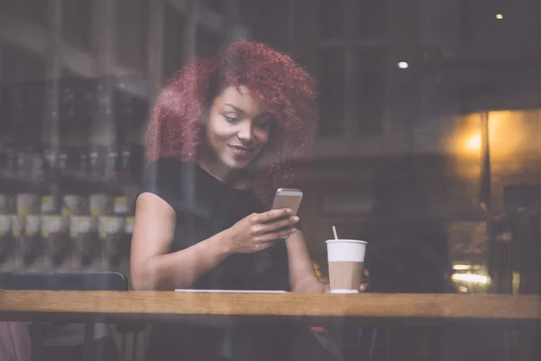 美丽的女孩在一家咖啡馆，在智能手机上打字 — 图库照片