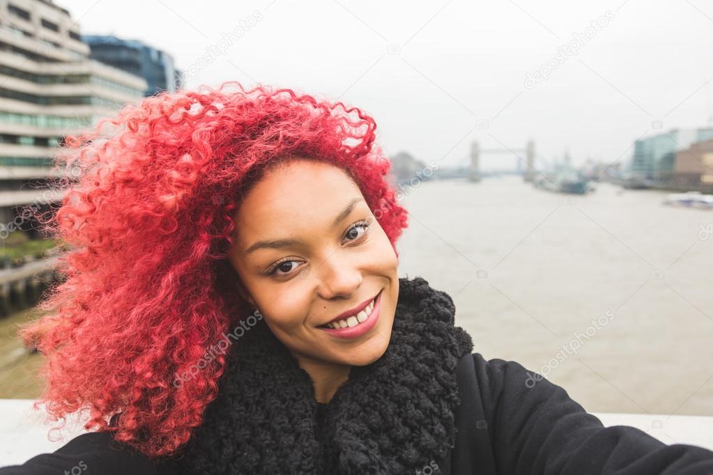 Girl taking selfie in London with Tower Bridge on background