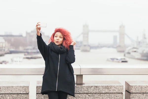 Menina tirando selfie em Londres com Tower Bridge no fundo — Fotografia de Stock