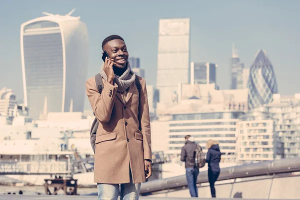Young man talking on mobile with London city on background — 图库照片