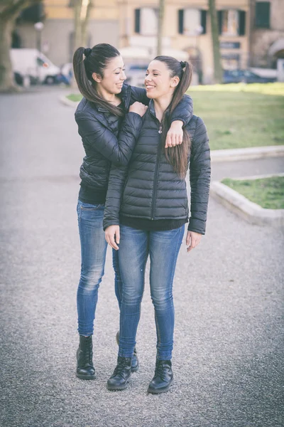 Femenino gemelos jugando juntos y disfrutar llegar piggyback paseo —  Fotos de Stock