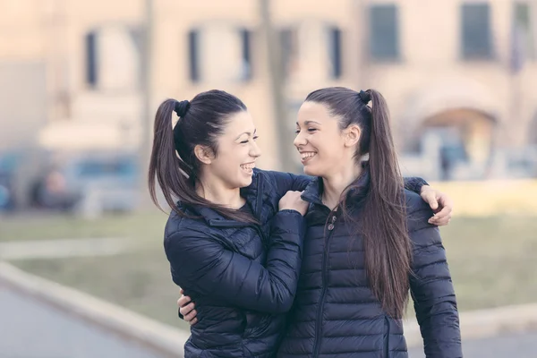 Femenino gemelos jugando juntos y disfrutar llegar piggyback paseo —  Fotos de Stock