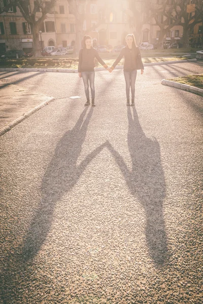 Skuggor av kvinnliga tvillingar hålla händer i staden. — Stockfoto