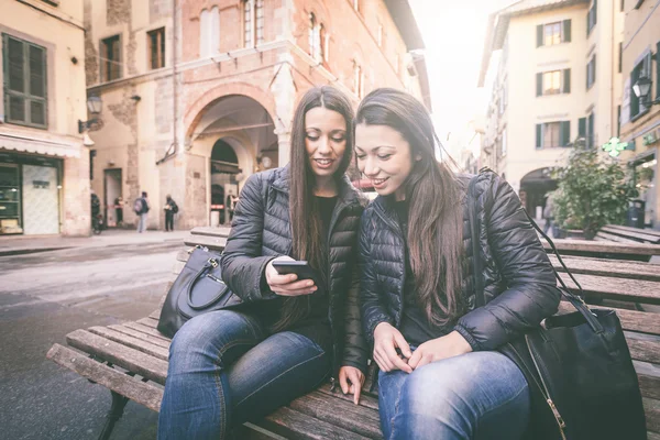 Két női ikrek látszó-on egy okos telefon — Stock Fotó