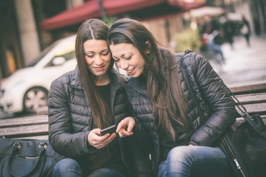 Bir akıllı telefon arayan iki kadın ikiz