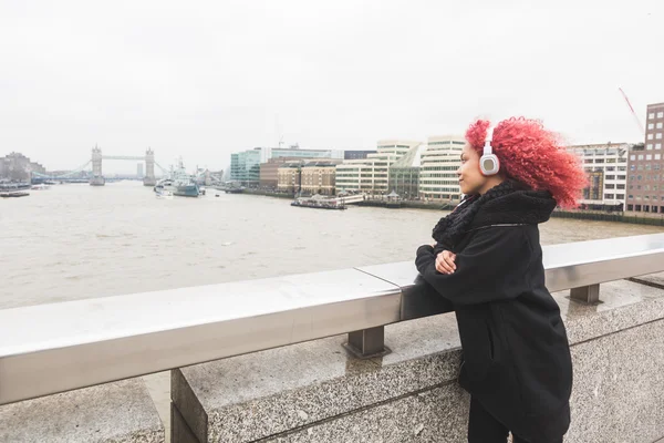 Vacker kvinna lyssnar musik i London — Stockfoto