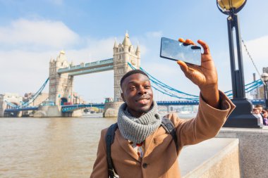 Man taking selfie in London with Tower Bridge on background
