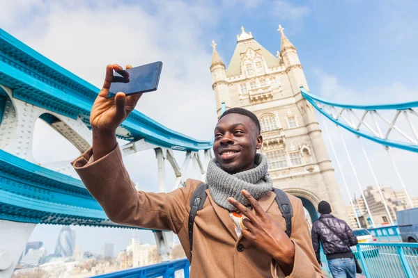 Man taking selfie in London with Tower Bridge on background — Stockfoto